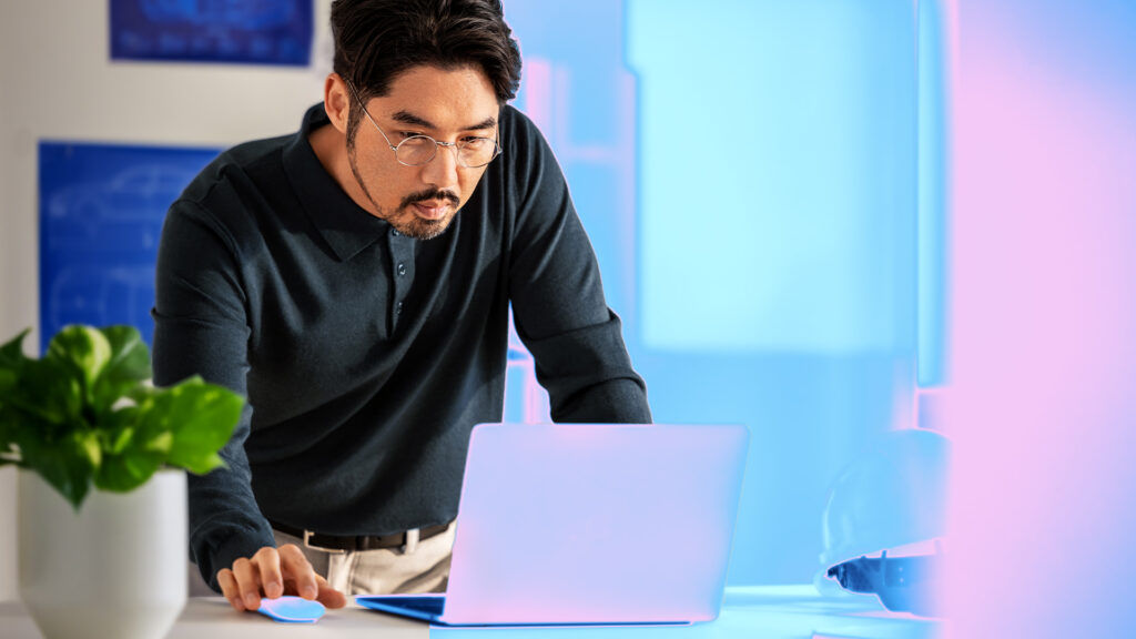 Electric car engineer in focused work in factory office on a laptop